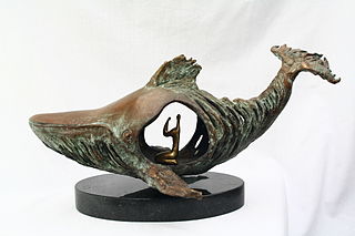 Foto de un escultura metalíca de un gran pez, con una figura humana al interior, en actitud de oración.