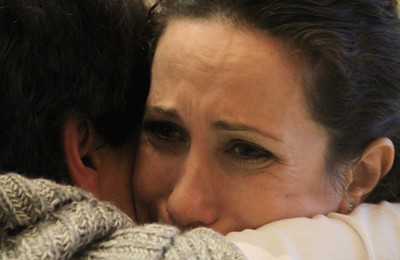 En esta fotografía se ve el rostro de una mujer que llora, mientras abraza a otro en señal de consuelo.